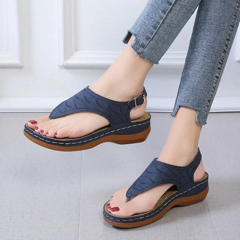 Women's wedge heel flip flop sandals with an adjustable buckle back strap in black.