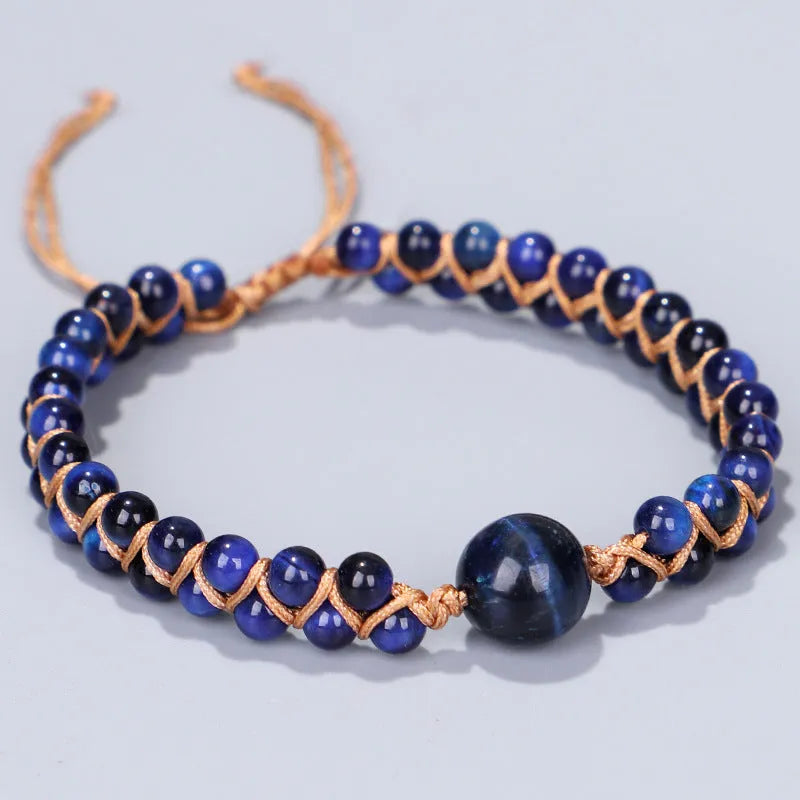 Handwoven geometric pull bracelet made from blue Tigereye stone on a wrist.