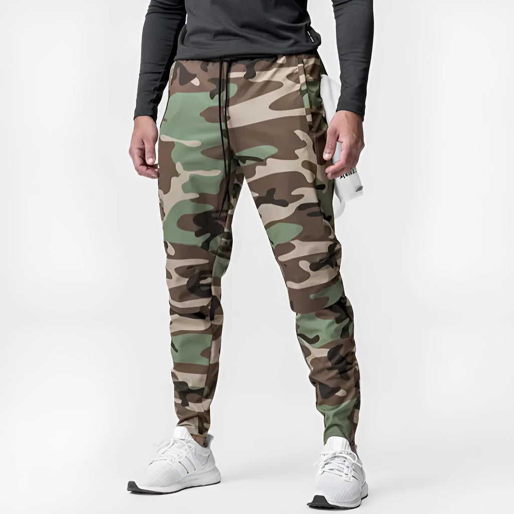 Men's loose grey fitness trousers with ankle ties on a gym floor.