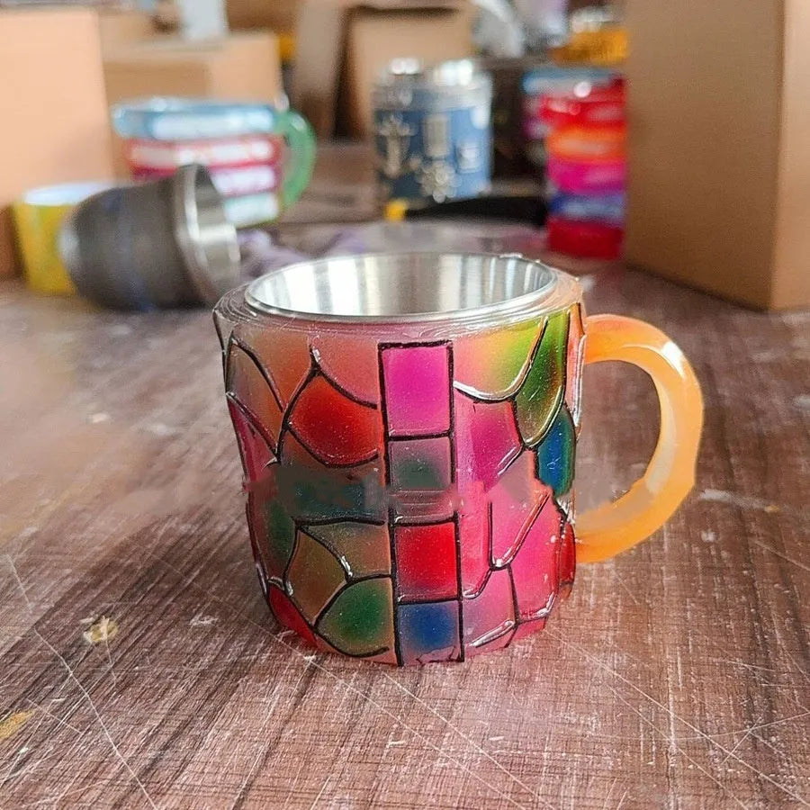 A painted synthetic resin coffee cup ornament with a bookmark design on its side.