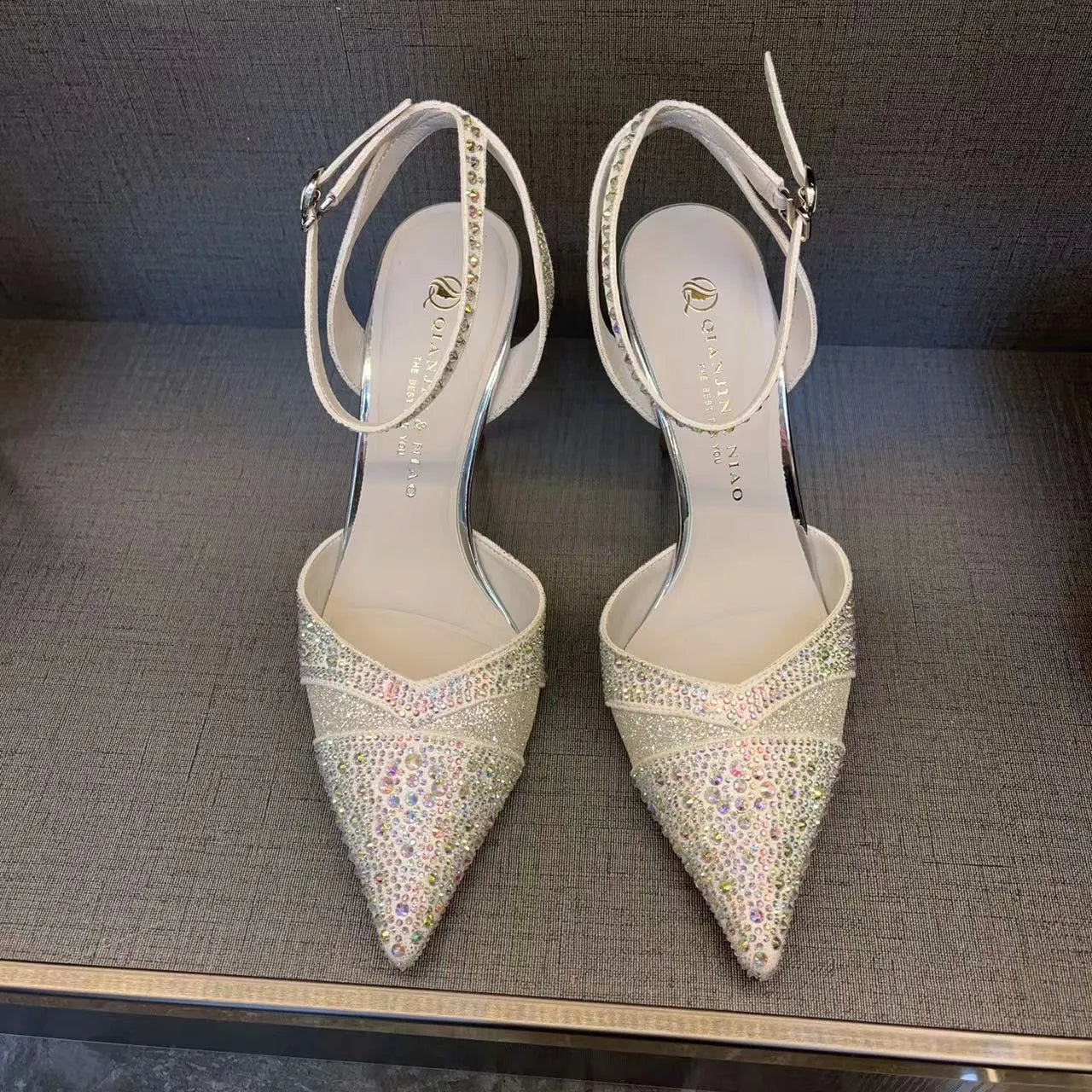 Women's silver hollow stiletto heels with pointed toe and red sole on white background