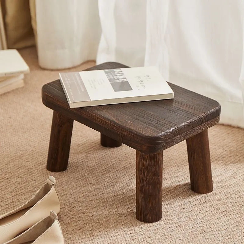 Rustic distressed wooden changing stool with bracket structure for shoe removal.