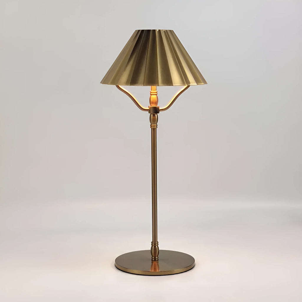 Gold-coloured alloy desk lamp with a cylindrical shade on a wooden desk.