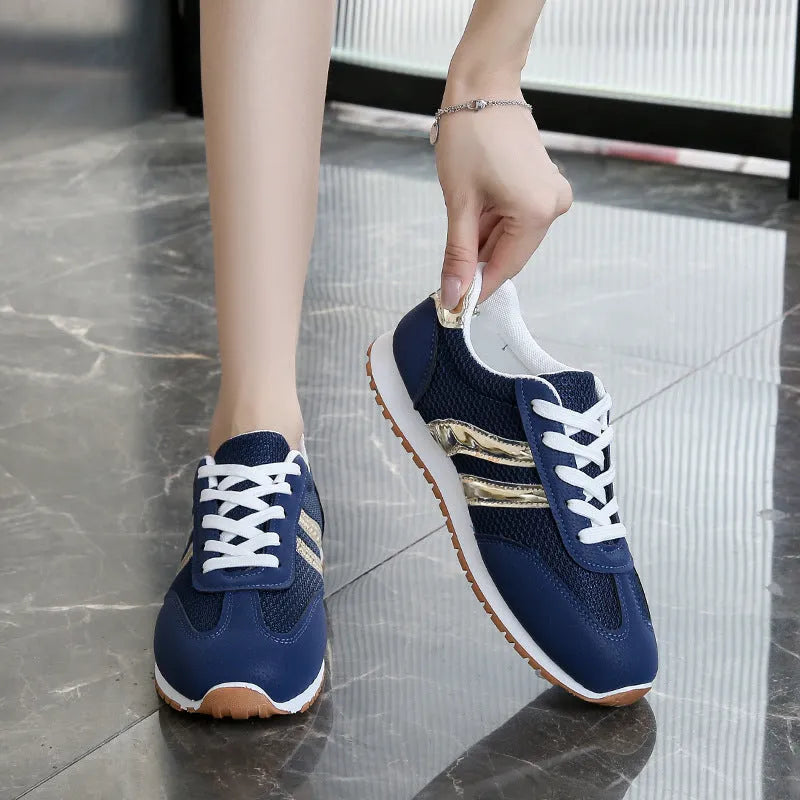 Blue women's casual tennis shoes with cross shoulder straps and white rubber sole on a flat heel.