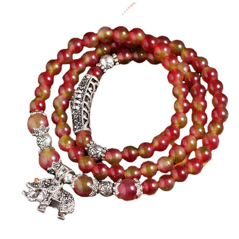 Natural watermelon crystal bracelet with a handmade Chinese knot closure, showing geometric beads.
