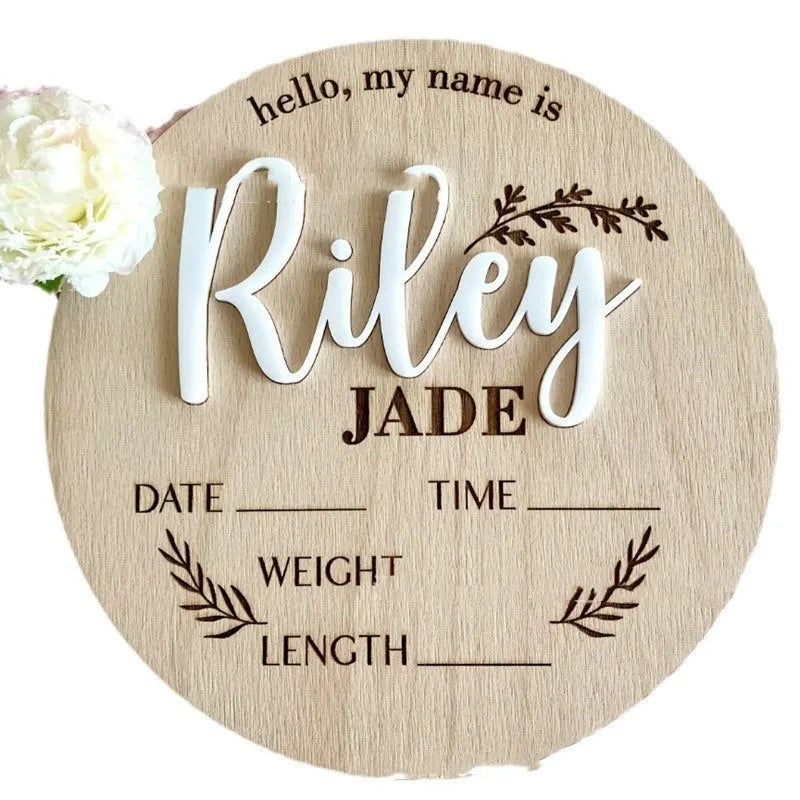 Square wooden newborn name label showing baby birth information and surname on a plywood plaque.