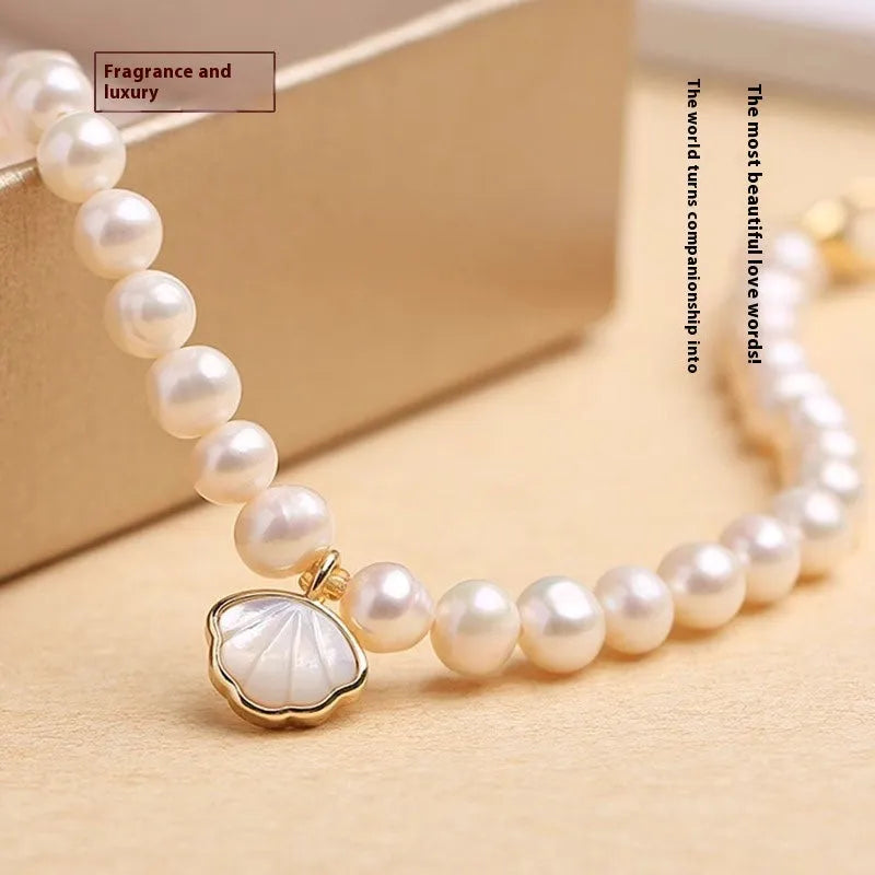 Women's freshwater pearl fan bracelet with alloy shell on wrist, showing elastic and chain closure options.