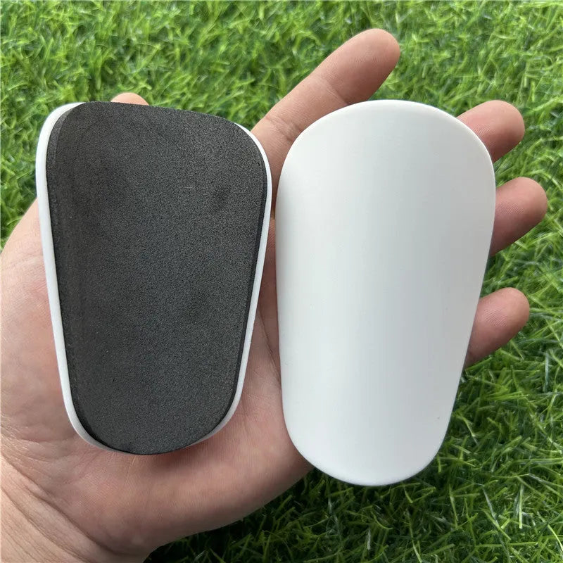 Pair of extra small black and white plastic football shin guards measuring 8x5cm for youth players