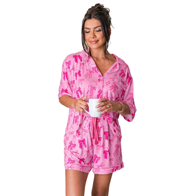 Pink women's pajama set with bow print, featuring a top and trousers made from lightweight polyester fabric.