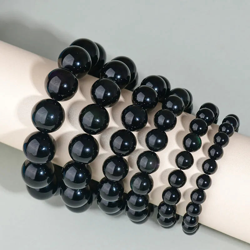 Hand-woven round obsidian bead bracelet in multiple colour options on a wrist.