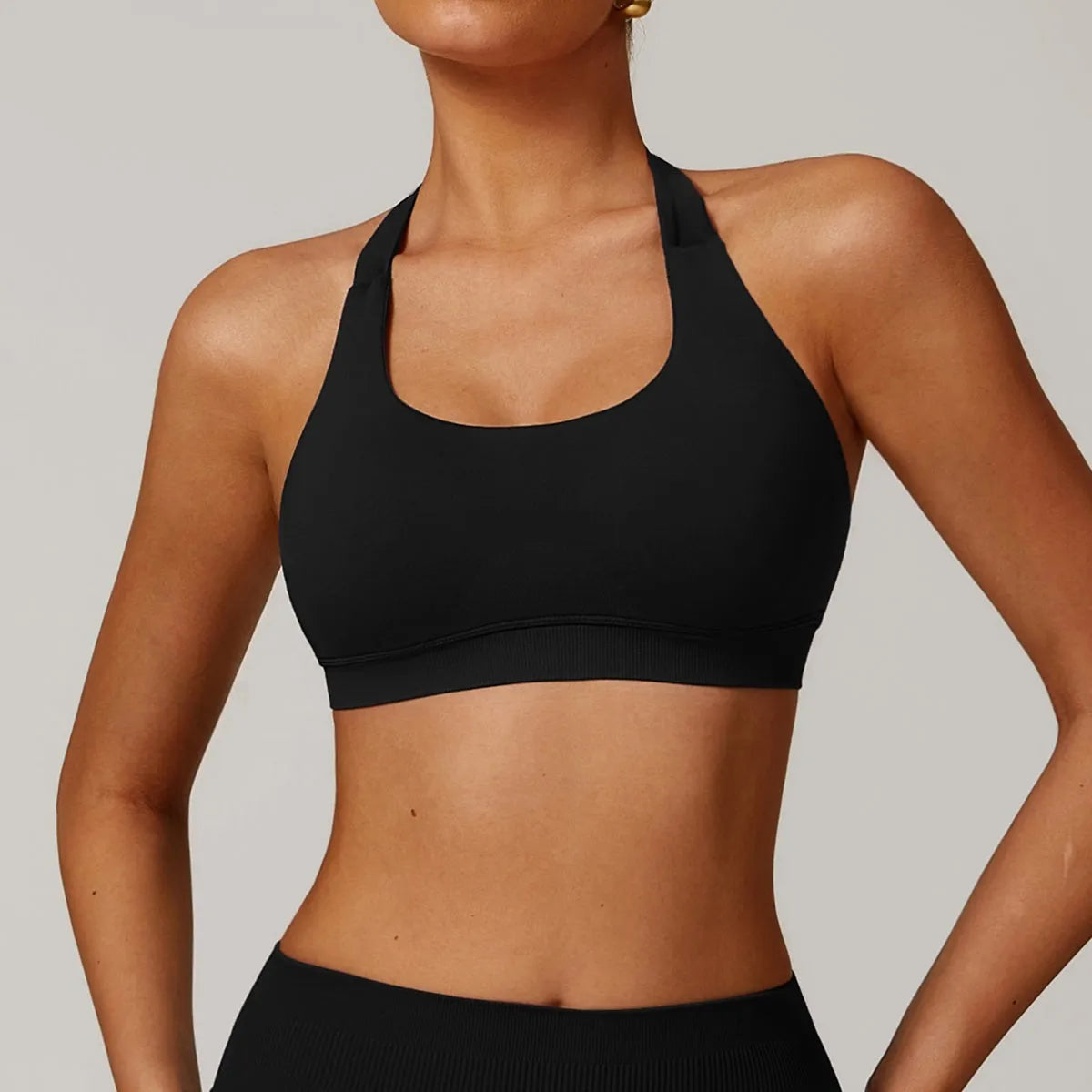 Women's black halter neck sports bra on a mannequin, showing medium support and removable padding.