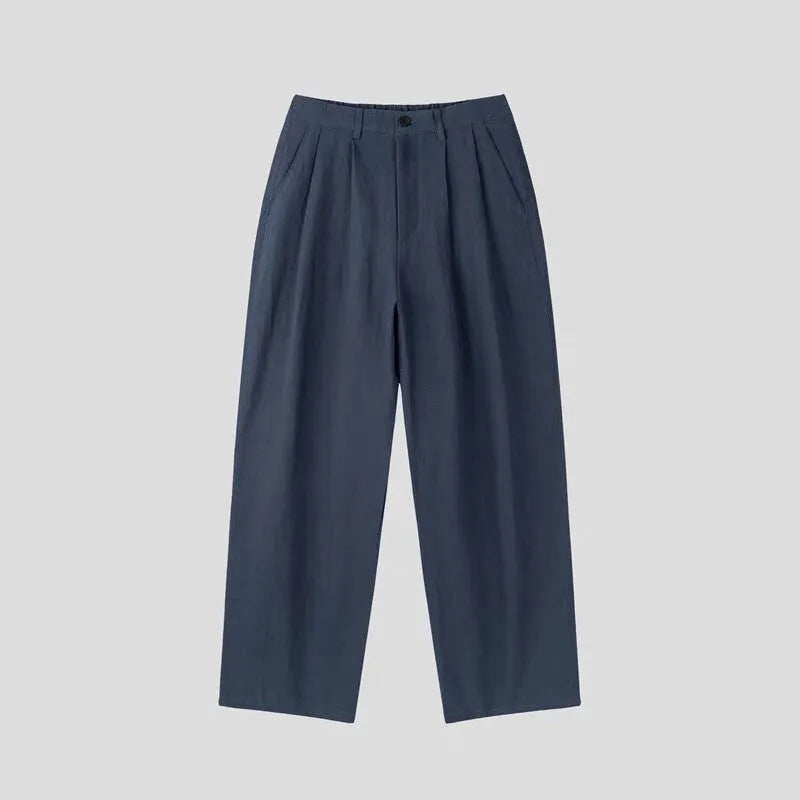 Man wearing apricot coloured loose wide-leg cotton linen trousers with a pencil leg opening.