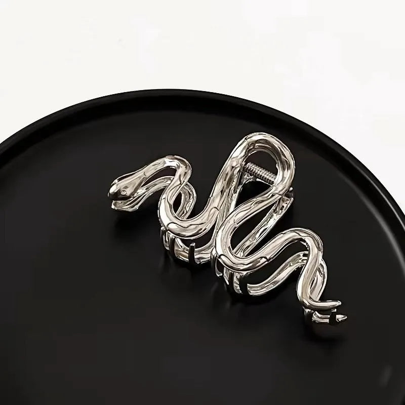 Silver metal Slytherin serpentine hair clip barrette measuring 10.5cm on a dark background