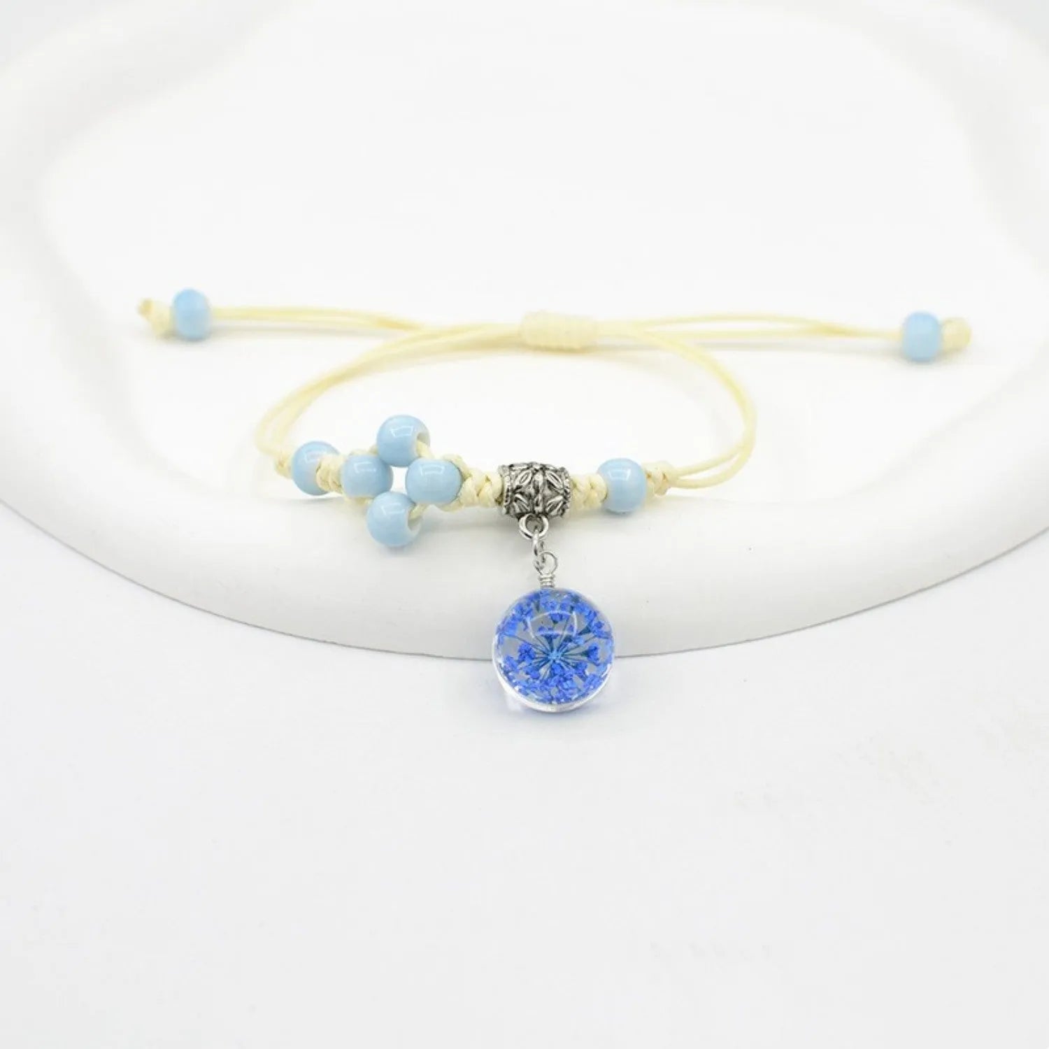 Close-up of a hand-woven glass bracelet with large 1.4 cm beads containing real dried flowers in multiple colour options.