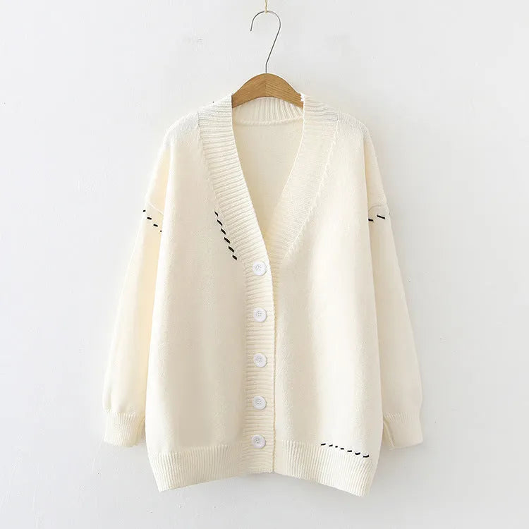 Women's loose fit black knitted cardigan top coat with long sleeves, hanging on a hanger.