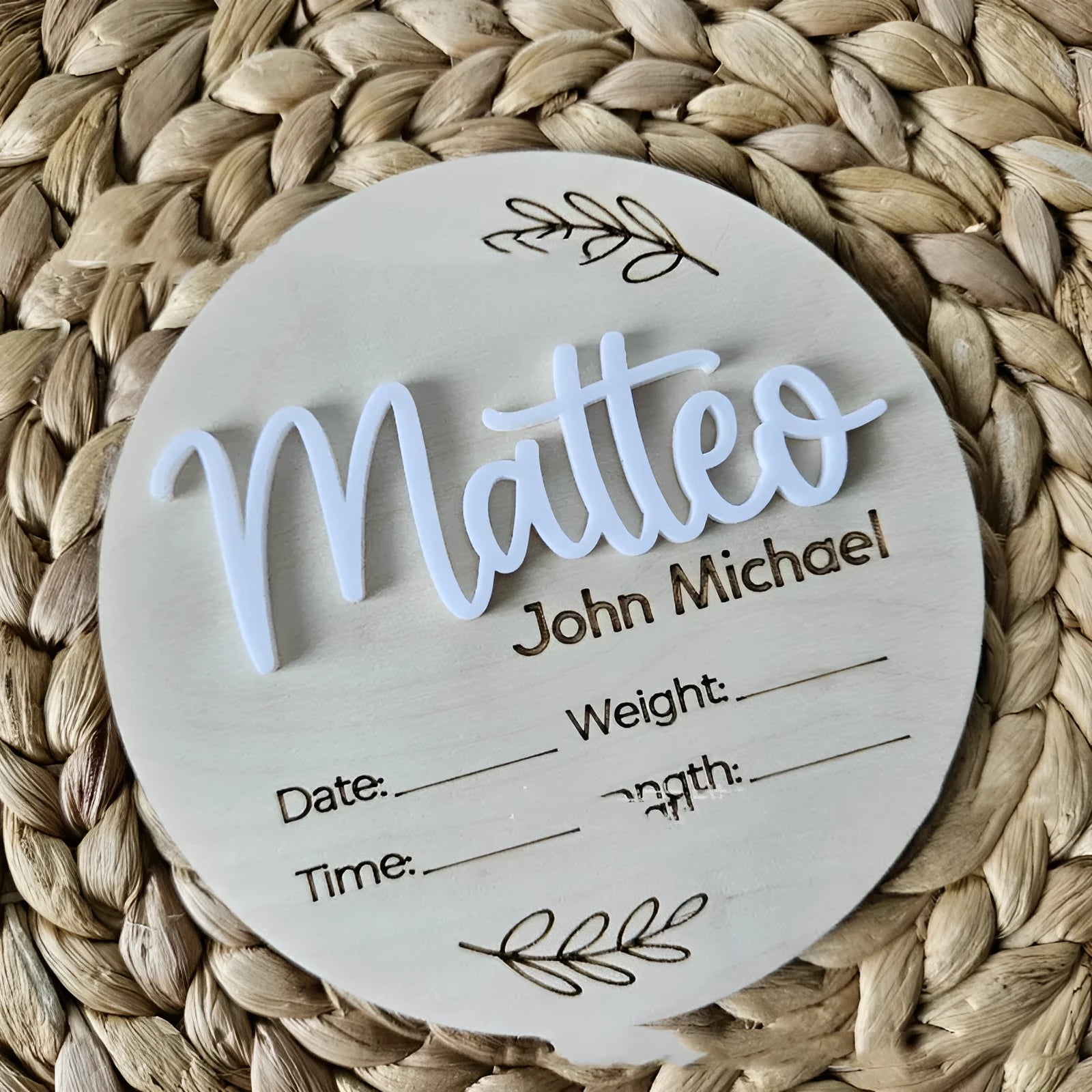 Square wooden newborn name label showing baby birth information and surname on a plywood plaque.