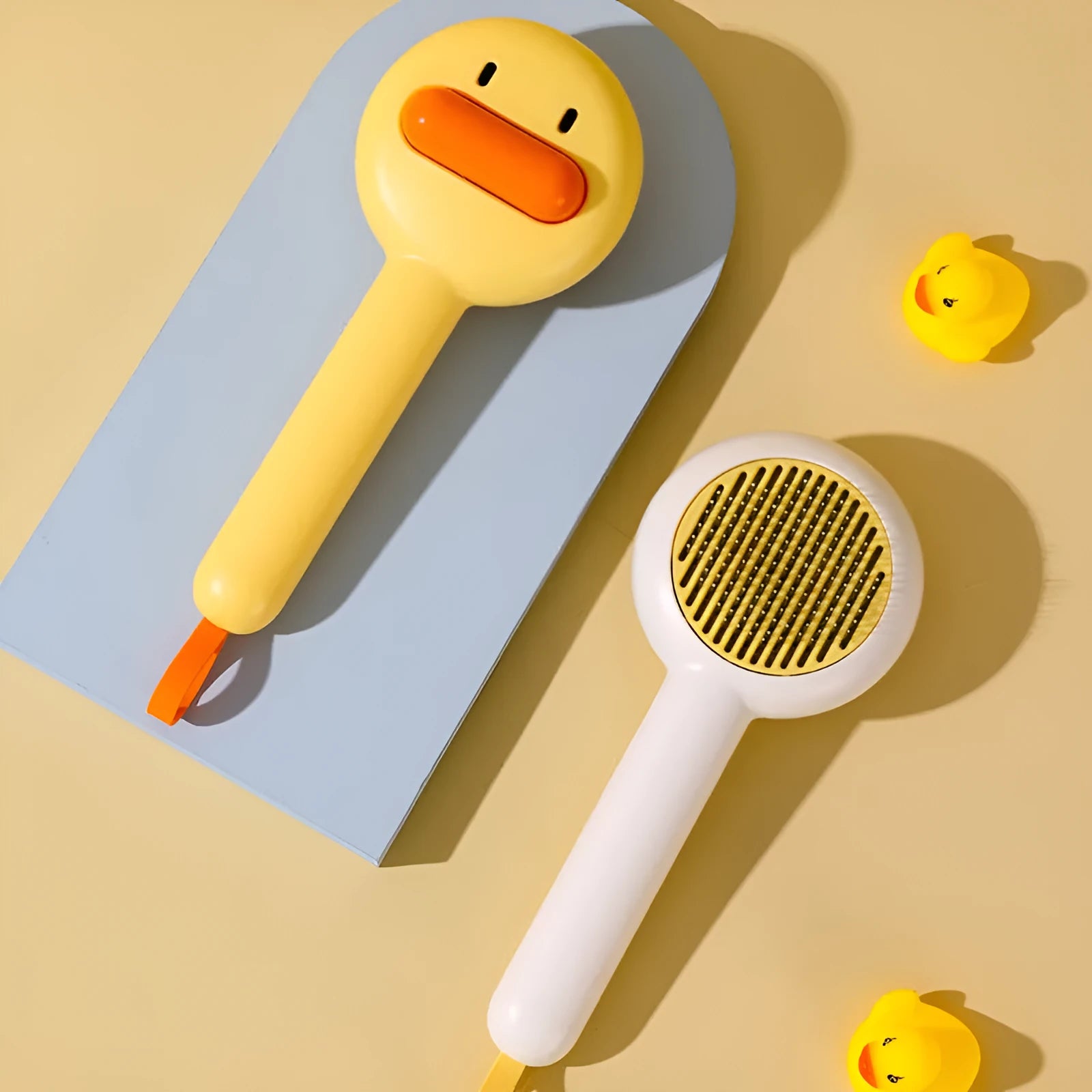 Small yellow duck-shaped pet grooming comb with open section and needle teeth