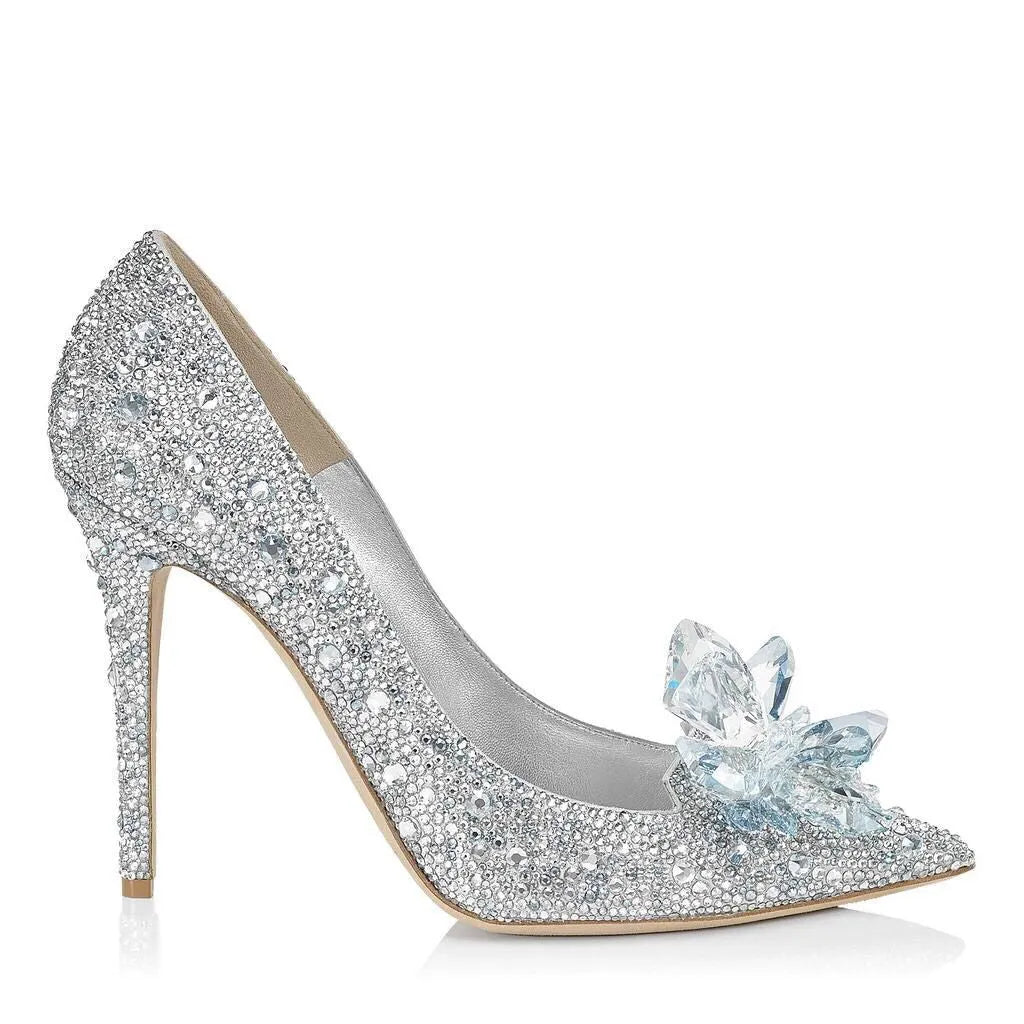 Gold women's pointed toe stiletto heels with rhinestone and bow decoration on a sequin cloth upper.