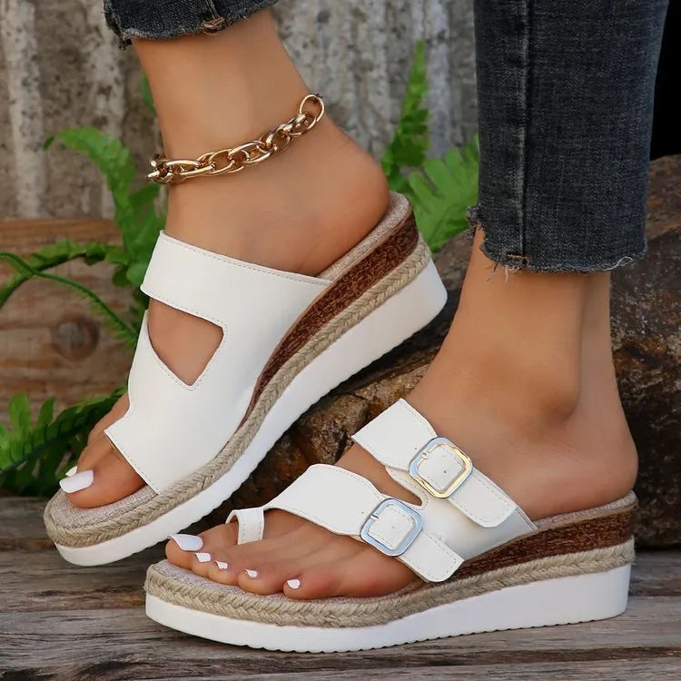 White wedge heel sandals with woven patent leather upper and peep toe design on neutral background