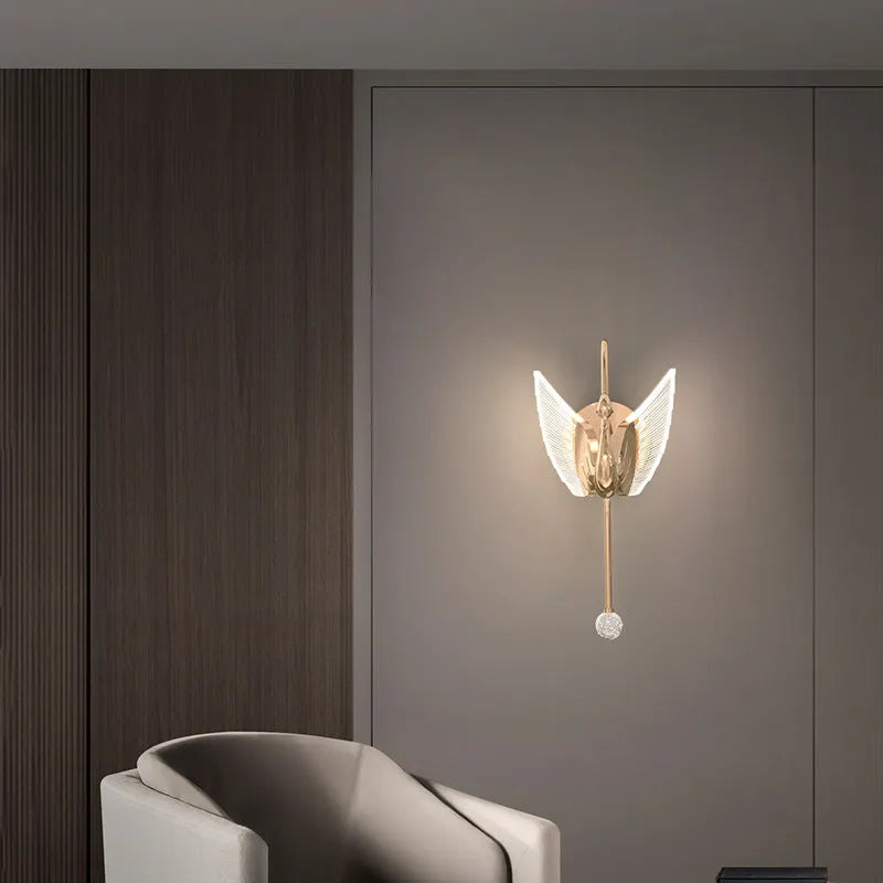 Gold minimalist swan wall lamp with acrylic shade mounted beside bed