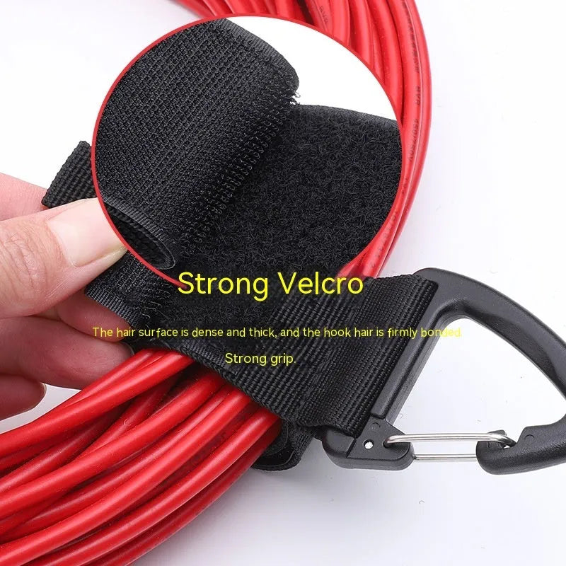 Black heavy-duty adjustable storage strap with metal carabiner clip for garage workshop organisation.