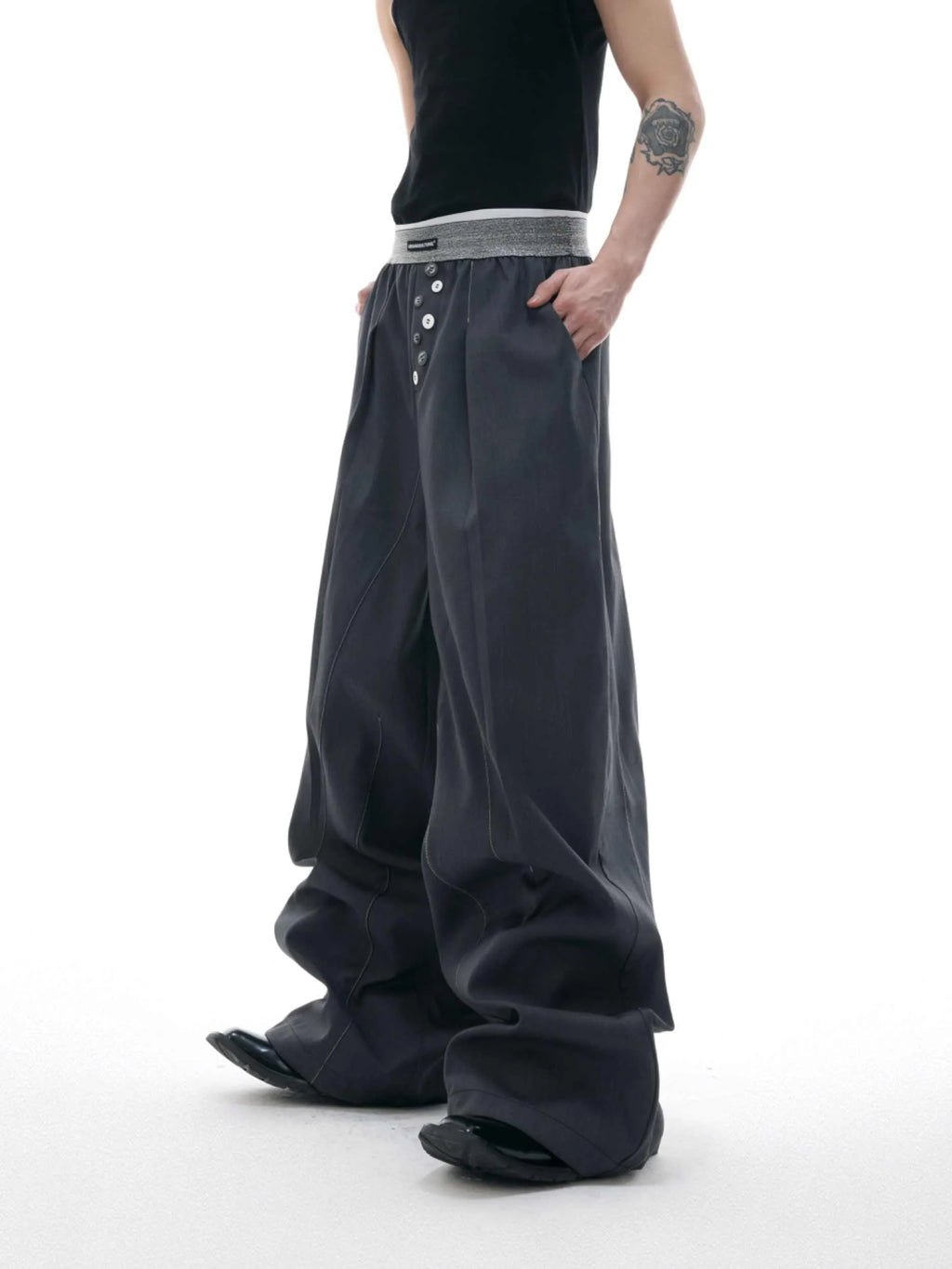 Men's grey straight-leg high-waisted trousers with a button-fly opening on a neutral background.