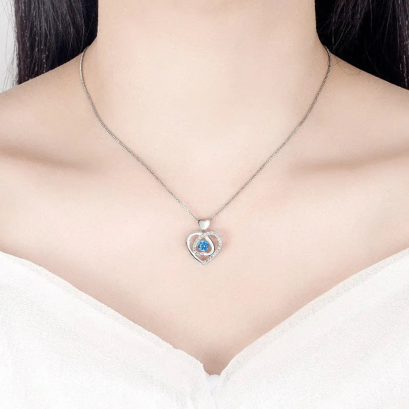 Blue diamond heart-shaped necklace and matching bracelet set with gemstone inlays on a model