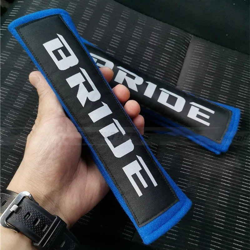 Pair of black car seatbelt shoulder pads with embroidered texture, showing dimensions.