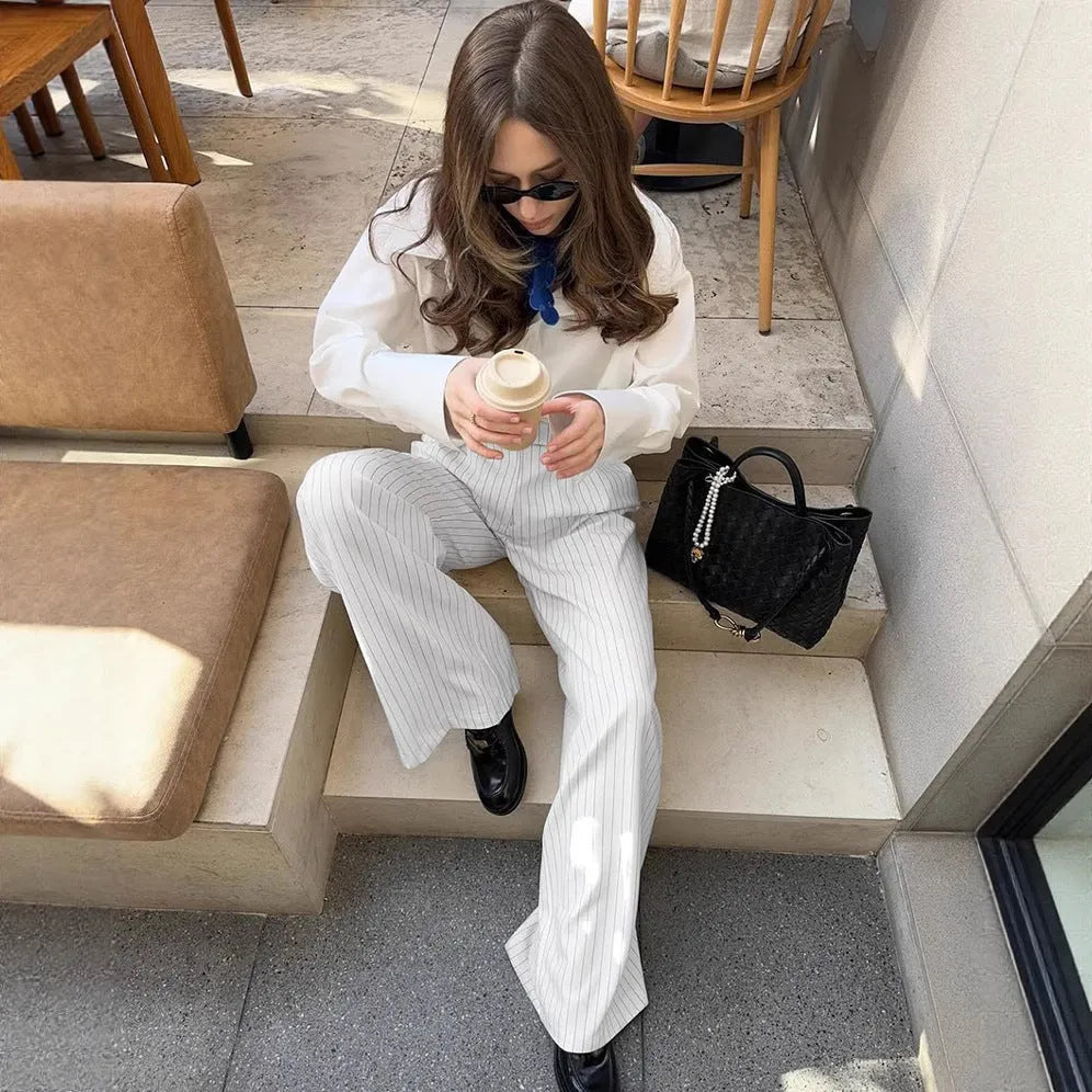 White striped wide-leg women's trousers with a front zipper on a hanger.