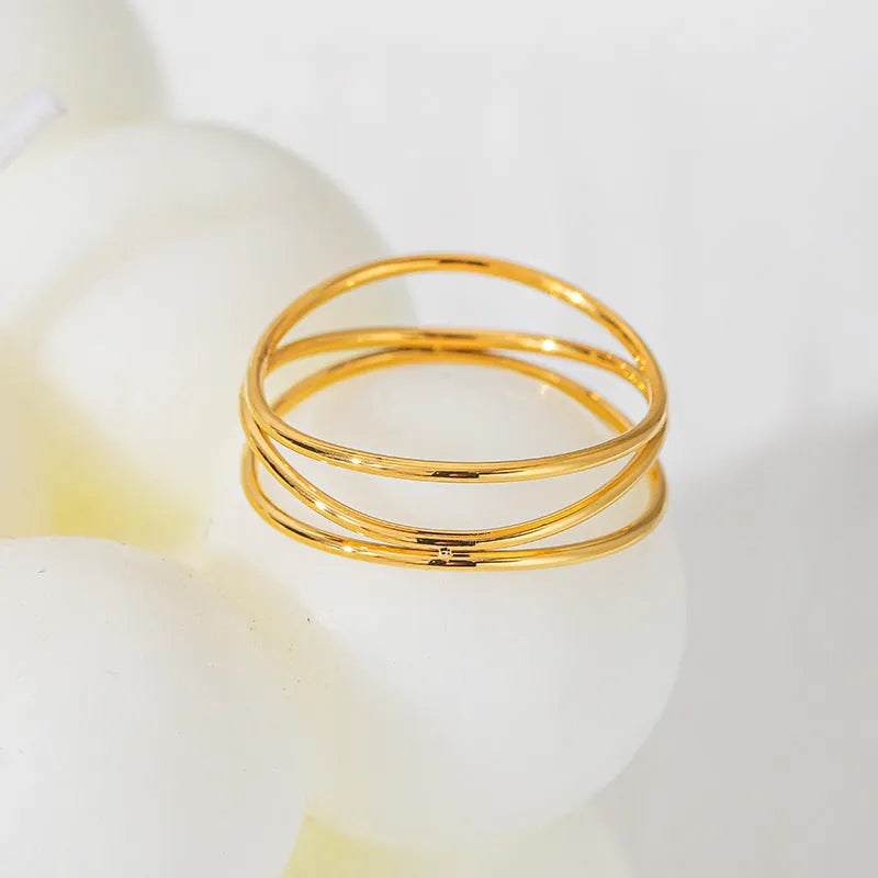 Gold geometric line ring with three-layer coil design on finger