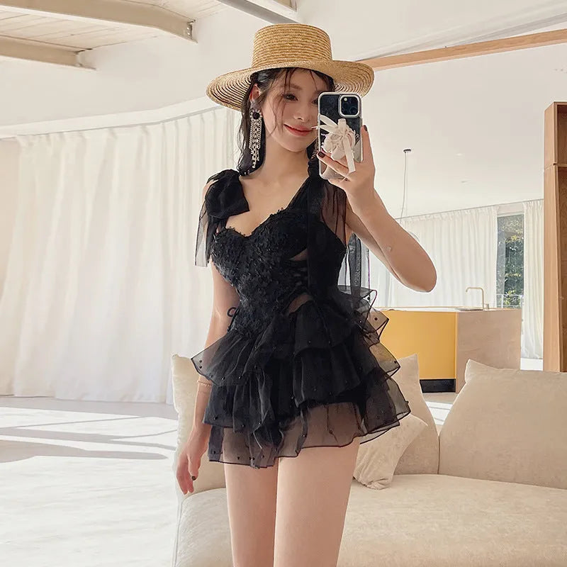 Black one-piece swimsuit with gathered chest design on a mannequin, showing sleeveless cut.