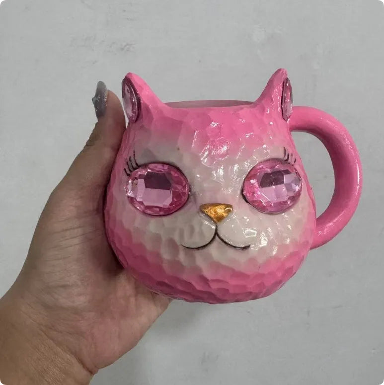 Coloured resin cat cup decoration in purple, green, blue, or pink on a shelf.