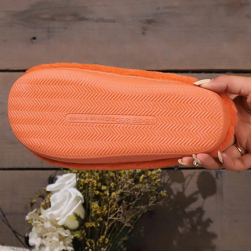 Orange pumpkin-themed plush slippers with a non-slip sole for indoor home wear.