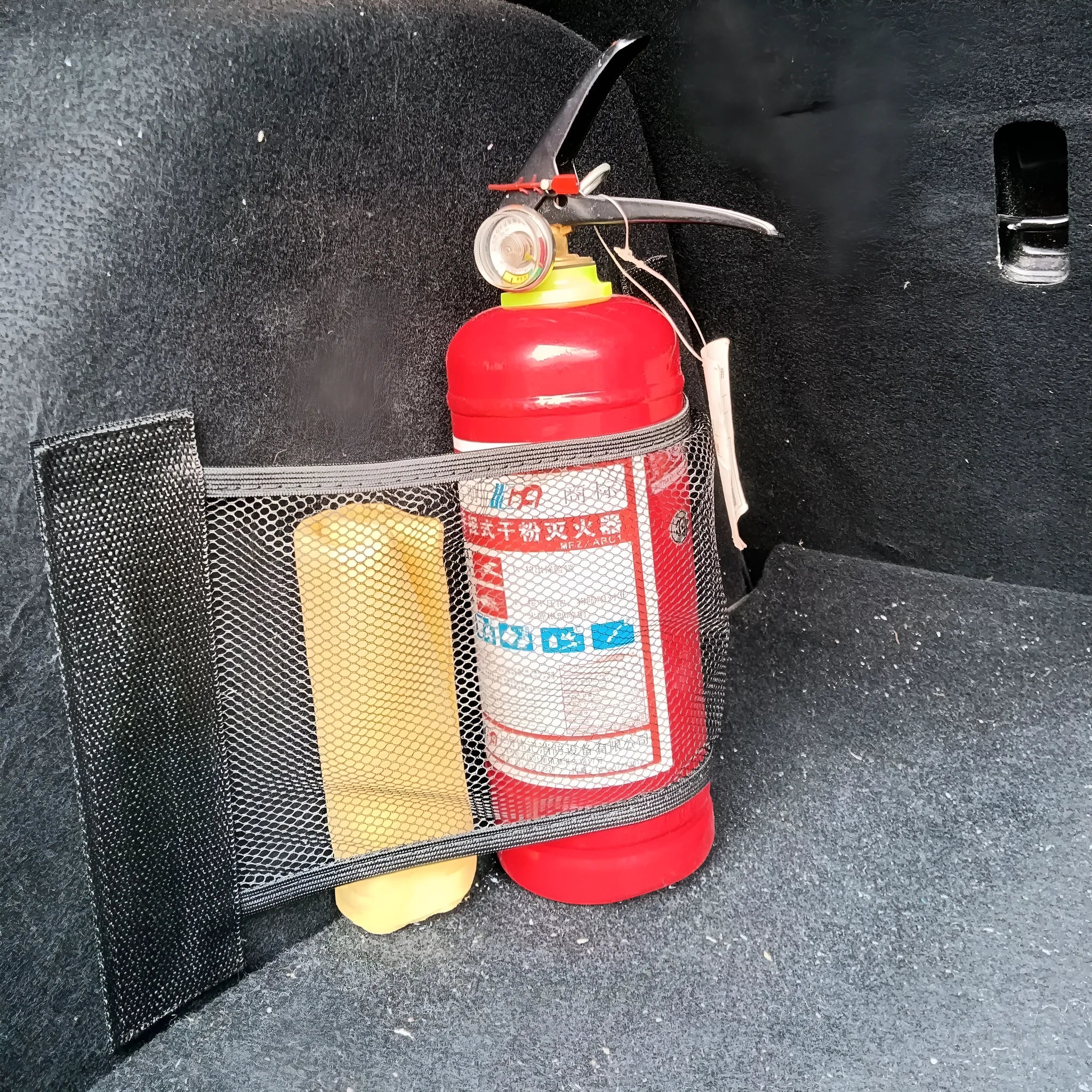 Elastic car boot storage net organiser holding various loose items securely in place