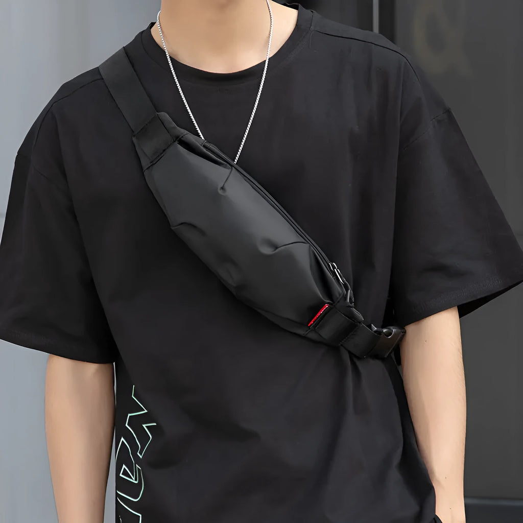 Black Oxford cloth crossbody waist pack showing front zipper and strap