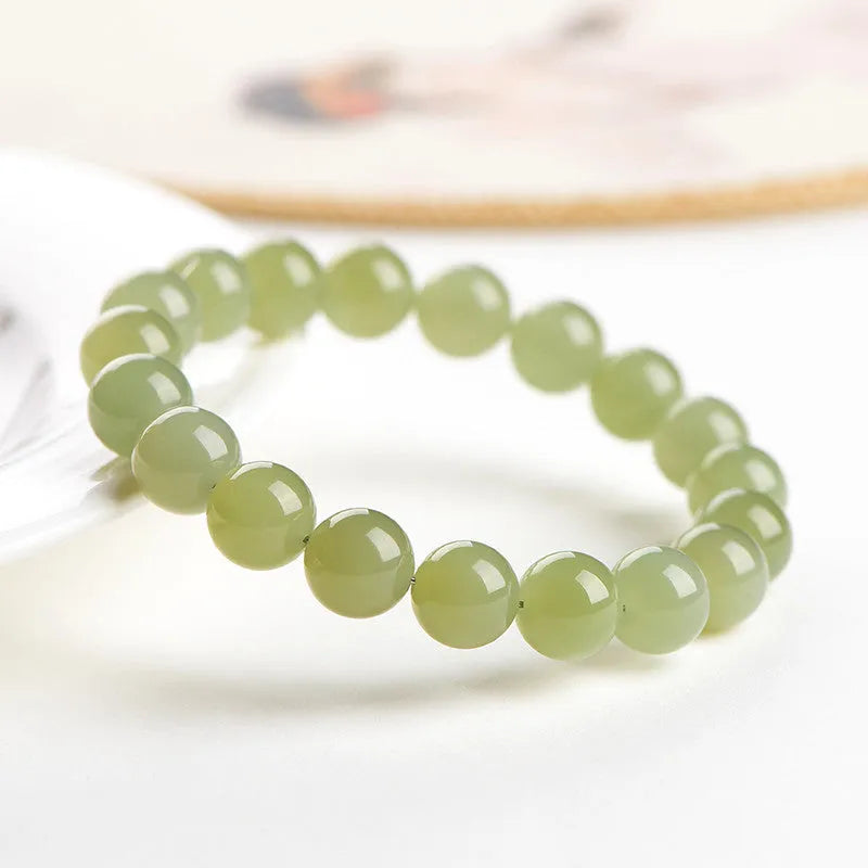 Hetian jade ball bracelet with polished beads in clear water colour on a string.