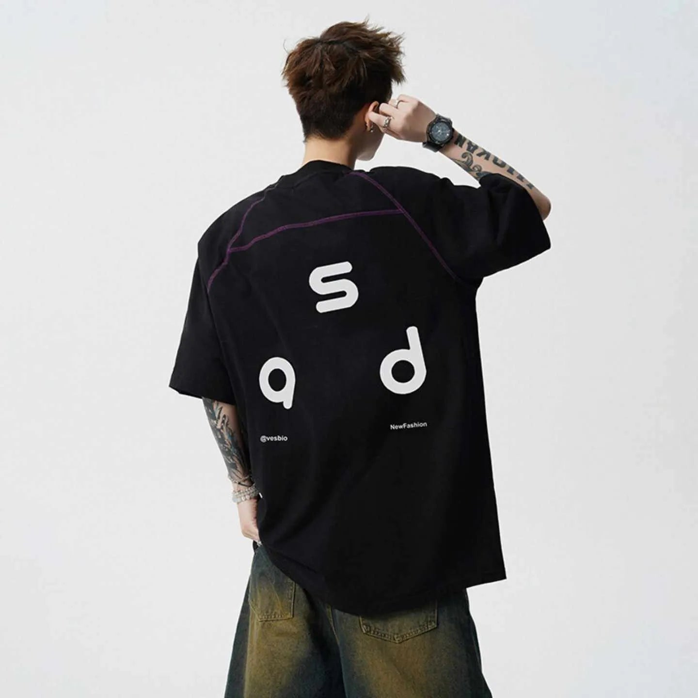 A loose-fitting black cotton short-sleeve T-shirt with a round neck on a hanger.