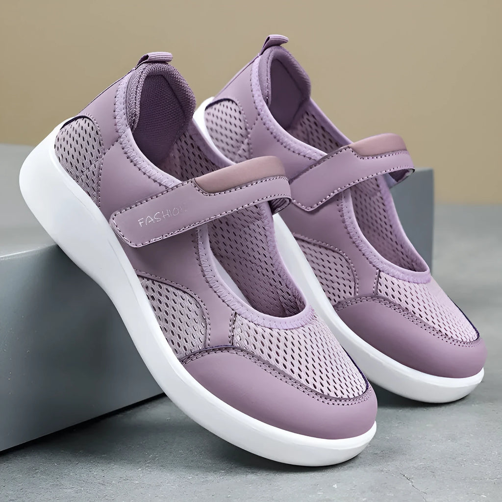 Women's grey mesh slip-on casual shoes with Velcro strap fastening on a flat sole.