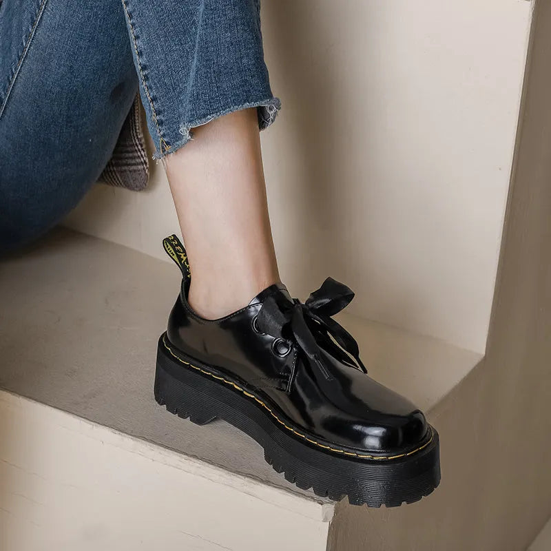 Women's black leather shoes with thick soles, ribbon cross-straps, and lace closure