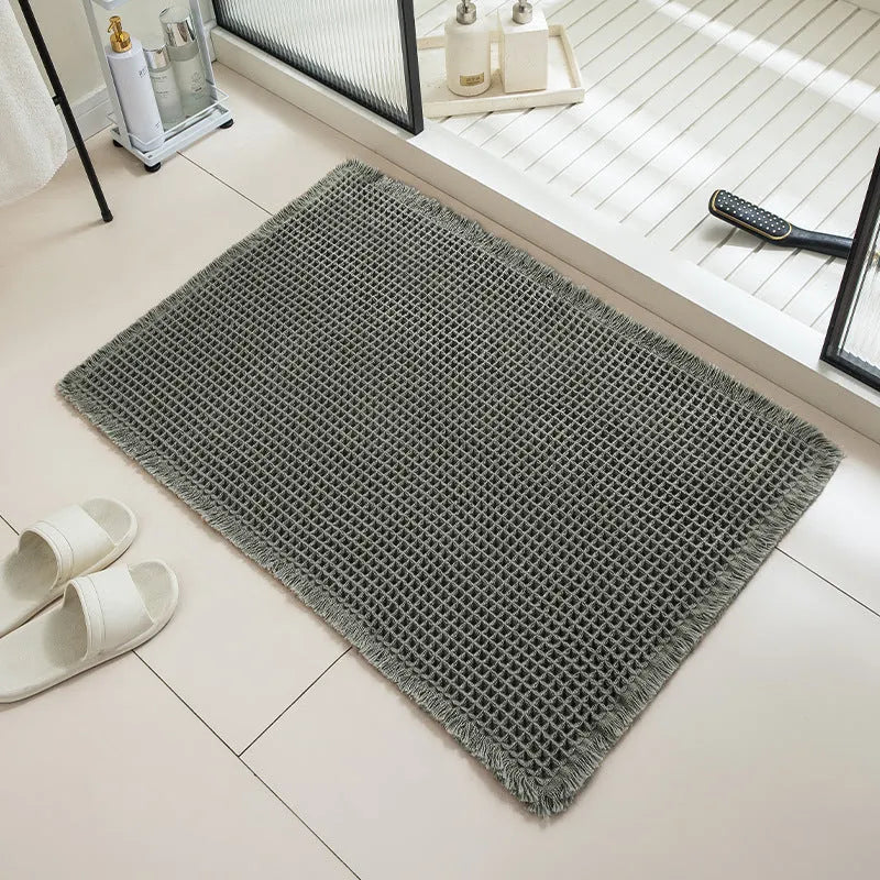 Modern checkered pattern absorbent non-slip bathroom floor mat in a neutral colour on tiled floor.