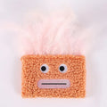 Colourful cat plush toy with a big mouth explosion head shape on a plain background.