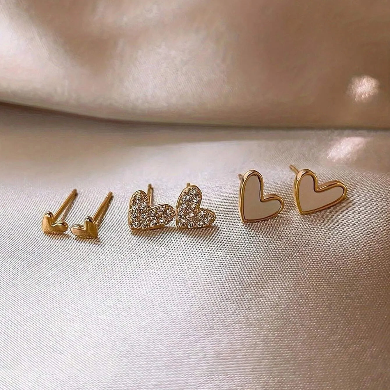Three pairs of heart shape alloy earrings with electroplated gold, black, pink, and black-white colour options