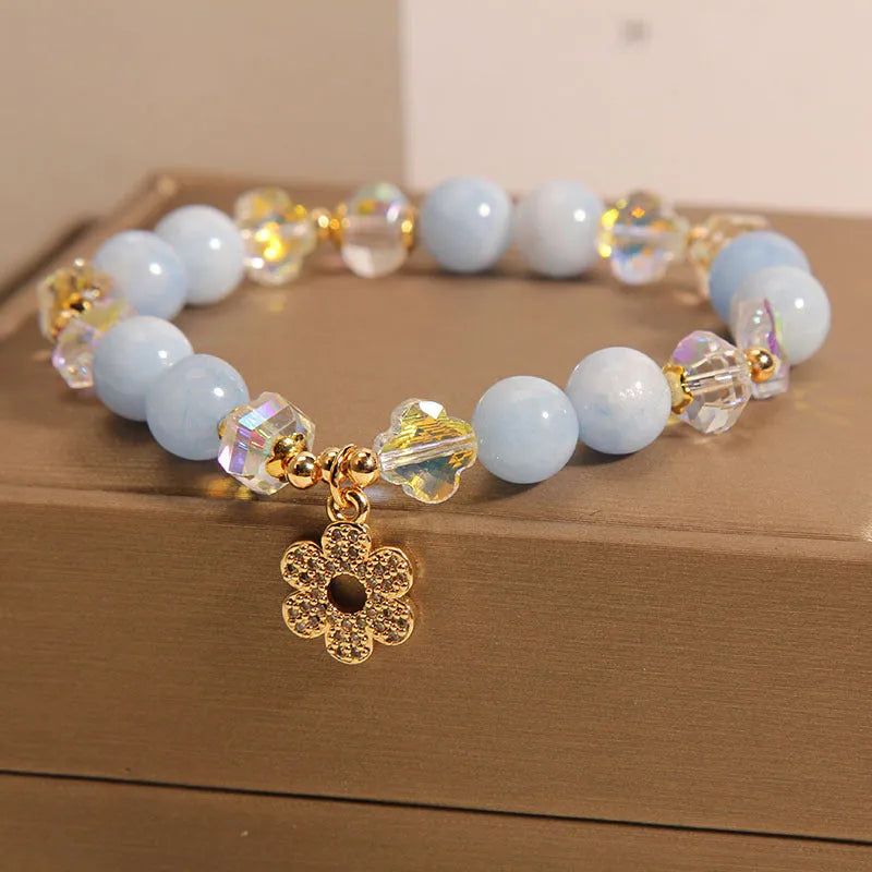 Women's aquamarine crystal four-leaf clover bracelet with pearl accents on a silver chain.