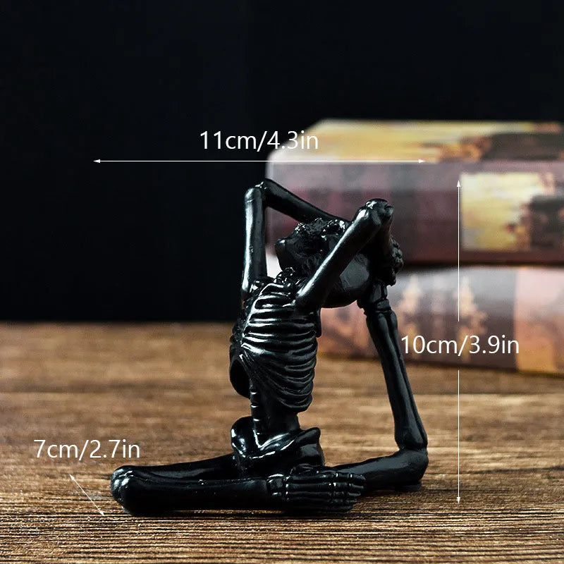 Detailed resin ornament of a yoga pose skeleton skull on a desktop, shown in black and white colour options.