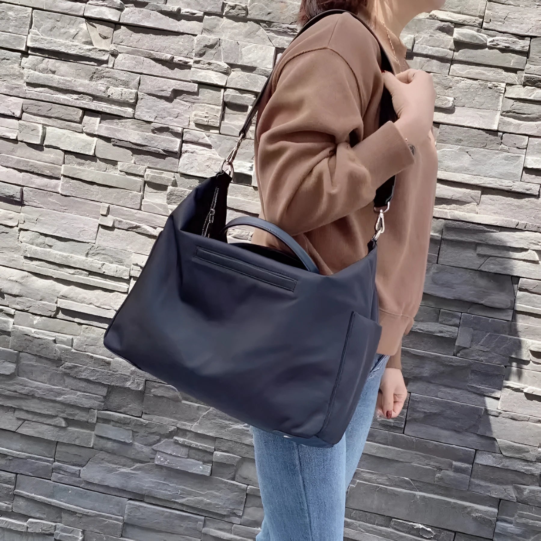 Black waterproof nylon shoulder bag with leather trim showing front view and interior