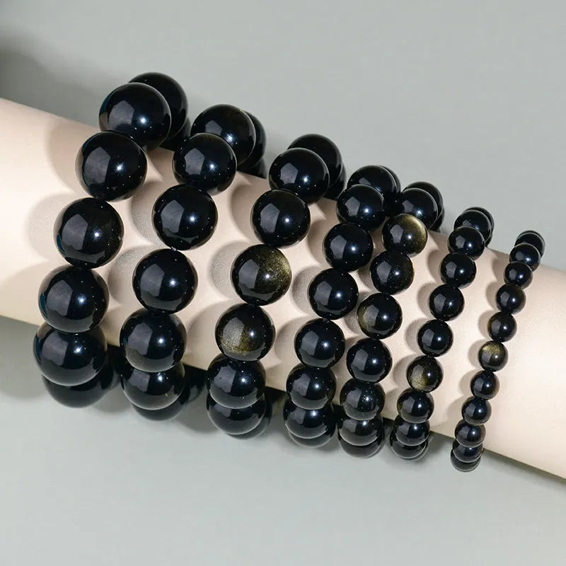 Hand-woven round obsidian bead bracelet in multiple colour options on a wrist.