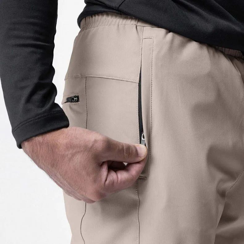 Men's loose grey fitness trousers with ankle ties on a gym floor.