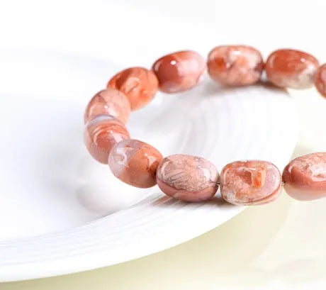 Natural cherry agate bracelet with barrel-shaped beads showing geometric design and Ruyi patterns