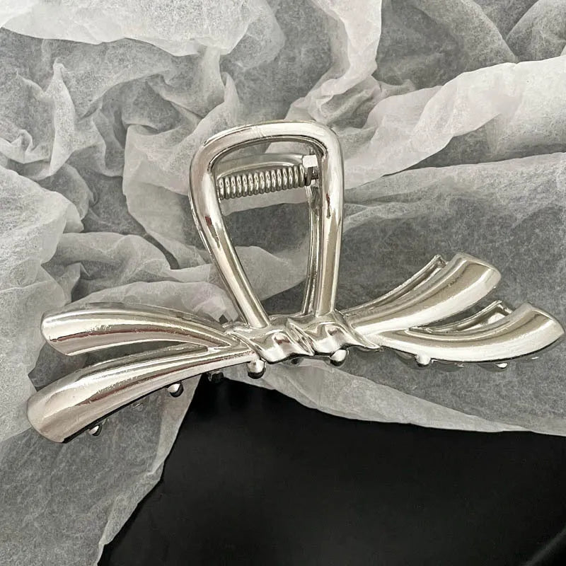 Silver metal hair claw clip assortment showing bows, waves, pearl designs, and geometric shapes from 4cm to 13.5cm