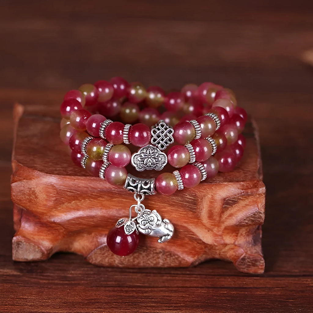 Natural watermelon crystal bracelet with a handmade Chinese knot closure, showing geometric beads.